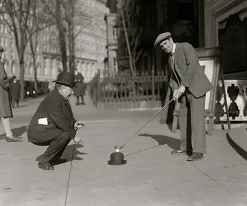 American singer and actor Al Jolson (R) prepares to strike a golf ball in a New York city street, 1923