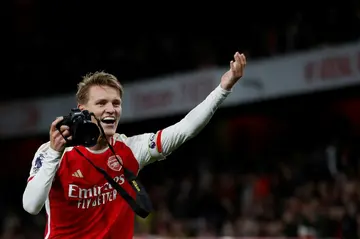Martin Odegaard picks up a camera and takes pictures after Arsenal's win over Liverpool