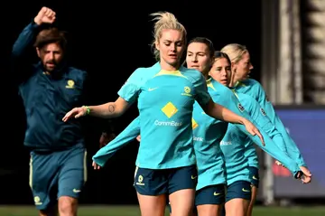 Australia's Ellie Carpenter (C) and her teammates go through their stretching exercises during a training session