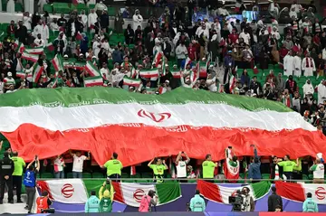 Iranian football fans hold up the national flag during Asian Cup semi-final against Qatar in Doha in  February