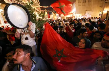 Morocco supporters in Doha's Souq Waqif celebrate their team's qualification for the last 16 of the World Cup