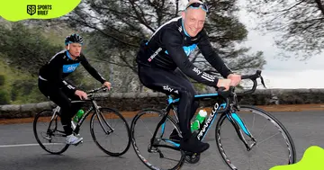 Dave Brailsford cycles with a member of Team Sky, a British professional cycling team