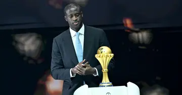 Former Ivorian footballer, Yaya Toure puts the trophy on stage during the Africa Cup of Nations official draw.