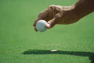 Golfer placing golf ball on turf