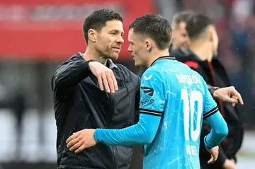 Bayer Leverkusen coach Xabi Alonso (L) and midfielder Florian Wirtz embrace on the sideline