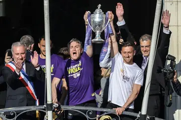 Damien Comolli (R) watches Toulouse's then coach Philippe Montanier and skipper Brecht Dejaegere hold the French Cup aloft after the club won the competition last season