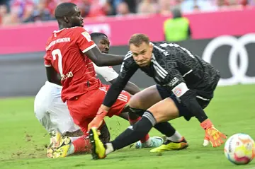 Marcus Thuram (C) squeezes the ball past Bayern Munich defender Dayot Upamecano (L) and goalkeeper Manuel Neuer to score for Borussia Moenchengladbach