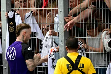 Germany's defender David Raum signs autographs for fans at a public training session in Jena, central Germany.