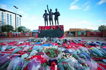 Floral tributes are pictured at the base of the 'United Trinity' statue, depicting former Manchester United players George Best, Denis Law and Bobby Charlton