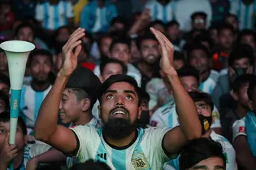 Football fans react as they watch the World Cup match between Poland and Argentina on a big screen in Dhaka