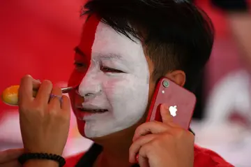A man gets facepainted outside Rajamangala National Stadium ahead of the exhibition football match between English Premier League teams Manchester United and Liverpool FC in Bangkok on July 12, 2022.