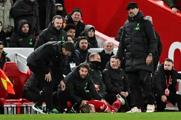 Liverpool manager Jurgen Klopp stands over injured defender Kostas Tsimikas