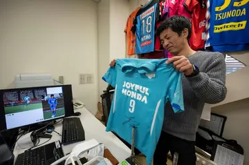 Masaaki Koido, a professor at Japan's University of Tsukuba, holds up Kaoru Mitoma's colleage football shirt