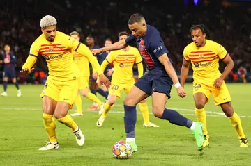 Kylian Mbappe competes with Ronald Araujo & Jules Kounde during the Champions League quarter-final first leg match between PSG and Barcelona.