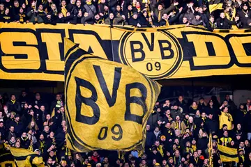 Dortmund fans wave flags during the Bundesliga soccer match between 1. FC Koeln and Borussia Dortmund at RheinEnergieStadion on January 20, 2024 in Cologne, Germany