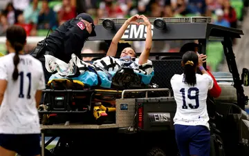 Injured US women's football star Mallory Swanson gestures to fans as she is stretchered off the field during Saturday's 2-0 win over Ireland in Austin