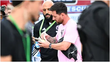 Lionel Messi signs an Argentina jersey while his bodyguard, Yassine Cheuko, looks on.