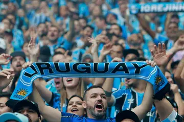 A Gremio fan holds up a Uruguay scarf