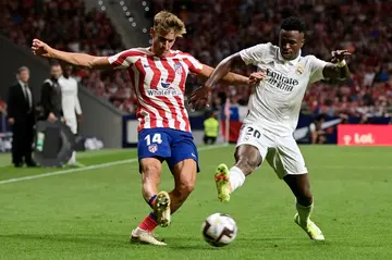 Real Madrid's Brazilian forward Vinicius Junior vies with Atletico Madrid's Spanish midfielder Marcos Llorente (L) during the derby between Atletico de Madrid and Real Madrid CF at the Wanda Metropolitano stadium in Madrid on September 18, 2022.