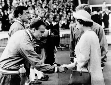 George Cohen, with teammate goalkeeper Gordon Banks hehind,  him, bows as he shakes hand with Queen Elizabeth II at Wembley stadium in London before the start of the World Cup