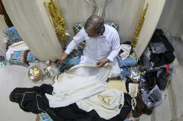 A Qatari man works on a traditional black and gold Arab bisht cloak at the Al Salim store in Doha's Souq Waqif