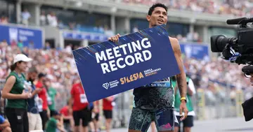 Wayde van Niekerk holds up a sign after setting a new meeting record.