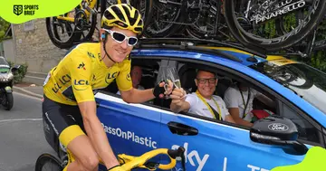 Geraint Thomas receives a champagne flute from team manager Dave Brailsford during a cycling event at the 105th Tour de France 2018