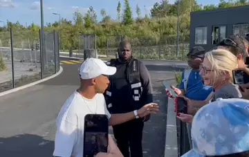 Kylian Mbappe (L) stops to greet fans at PSG's training grounds in Poissy, outside Paris, on July 22