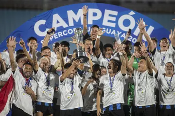 Alan Medina, captain of Liverpool, lifts the trophy to celebrate with his teammates after winning the match between Nacional and Liverpool at Centenario Stadium