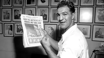 Examining irrefutable evidence of his victory in The Daily News, boxer Rocky Marciano displays his lethal left
