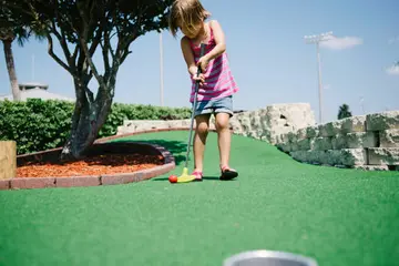 Girl playing miniature golf on a sunny day