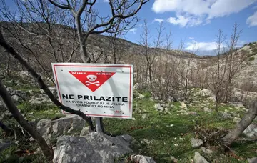 A sign reading "Mines - Keep out!" near a burned-out stone house on the slopes of Croatia's Velebit mountain, where Luka Modric's grandfather lived