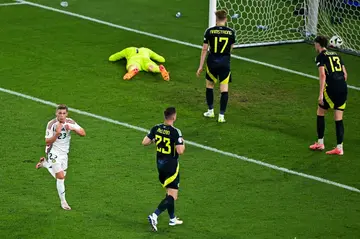 Kevin Csoboth (L) sprints past dejected Scotland players after scoring Hungary's winner in the 10th minute of added time