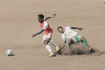 Mekelle 70 Enderta midfielder Yohannes Tsegay, centre, fights for the ball with a Raya Azebo defender during a match at the Mekele stadium