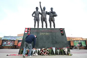 After Bobby Charlton's death was announced, Manchester United supporters laid tributes at the base of a sculpture of him, George Best and Denis Law outside Old Trafford