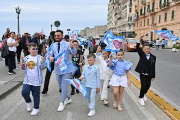 Dressed for success: a Neapolitan family takes a Sunday stroll on the seafront wearing Napoli colours