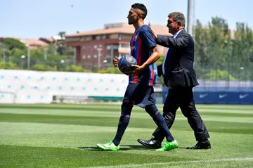 Raphinha walks out with  club president Joan Laporta at the Barcelona training centre to sign his contract