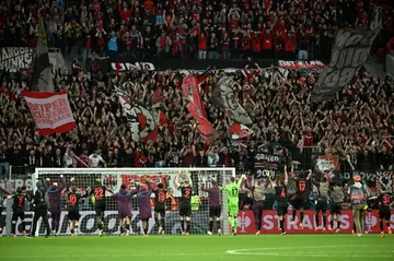 Bayer Leverkusen's players celebrate with fans after their Europa League quarter-final first leg victory against West Ham, with the German side on course for a stunning undefeated treble this season