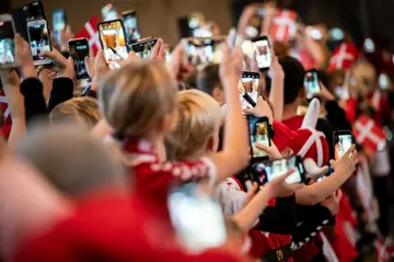 Children take pictures as they wave off the Doha-bound Denmark national team at Copenhagen airport