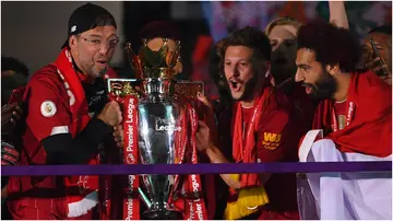 Jurgen Klopp, Adam Lallana, and Mohamed Salah celebrate with the Premier League trophy after Liverpool's match against Chelsea at Anfield on July 22, 2020.