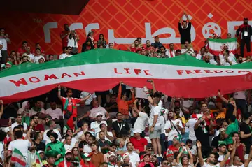 Iran supporters wave their national flag bearing the words "Woman, Life, Freedom"