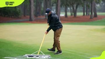 A member of the cleaning crew squeezing water out of the golf field