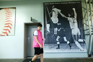 A young athlete walks past a poster showing Pele and defender Robert "Bobby" Smith at a sports academy now run by Smith in New Jersey