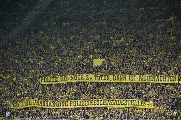 Dortmund fans hold a banner reading 'Police Do(rtmund) - killing two more times and then it will be Christmas - For an independent police complaints office' on Saturday.