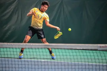 A man in yellow jersey hitting a tennis ball