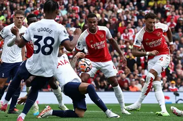 Tottenham's Cristian Romero (C) blocks Ben White's shot with his hand