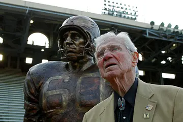 Chuck Bednarik stands next to his bust at the Pennsylvania University