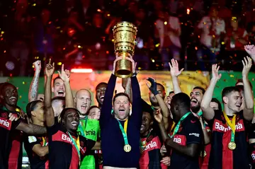 Xabi Alonso lifts the German Cup flanked by his Leberkusen players