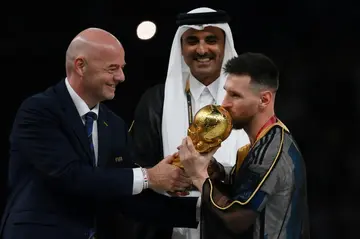 Infantino hands the World Cup trophy to Lionel Messi as the emir of Qatar watches on, following Argentina's win over France in the final in Doha in December