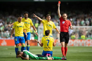 Spanish referee Guillermo Cuadra Fernandez (R) shows a red card to Real Betis' Spanish midfielder Sergio Canales